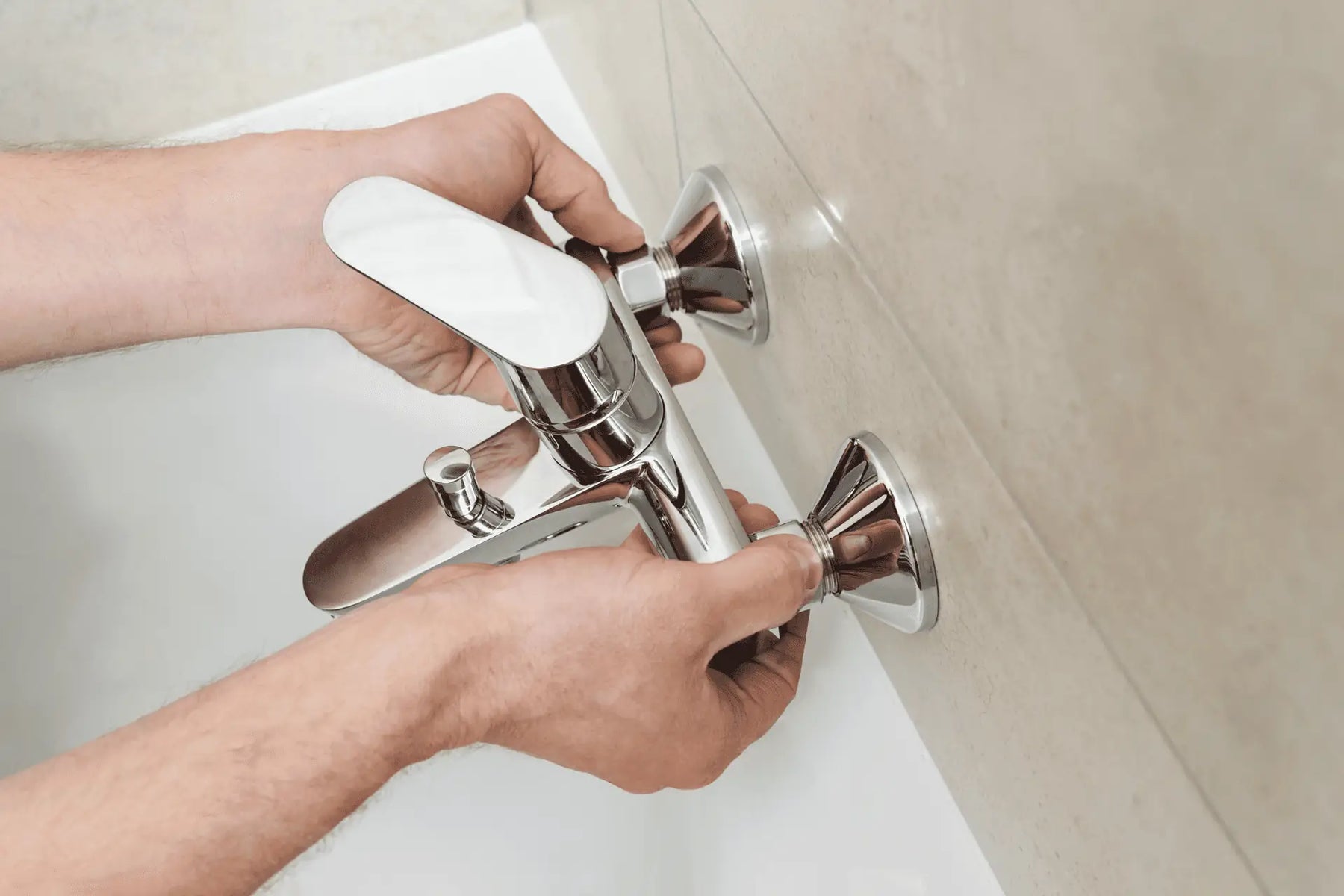 A person installs a brand new single handle faucet in a bathtub