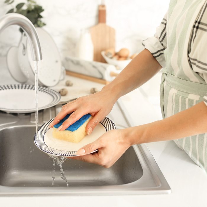 Person washing dirty dishes in a single sink