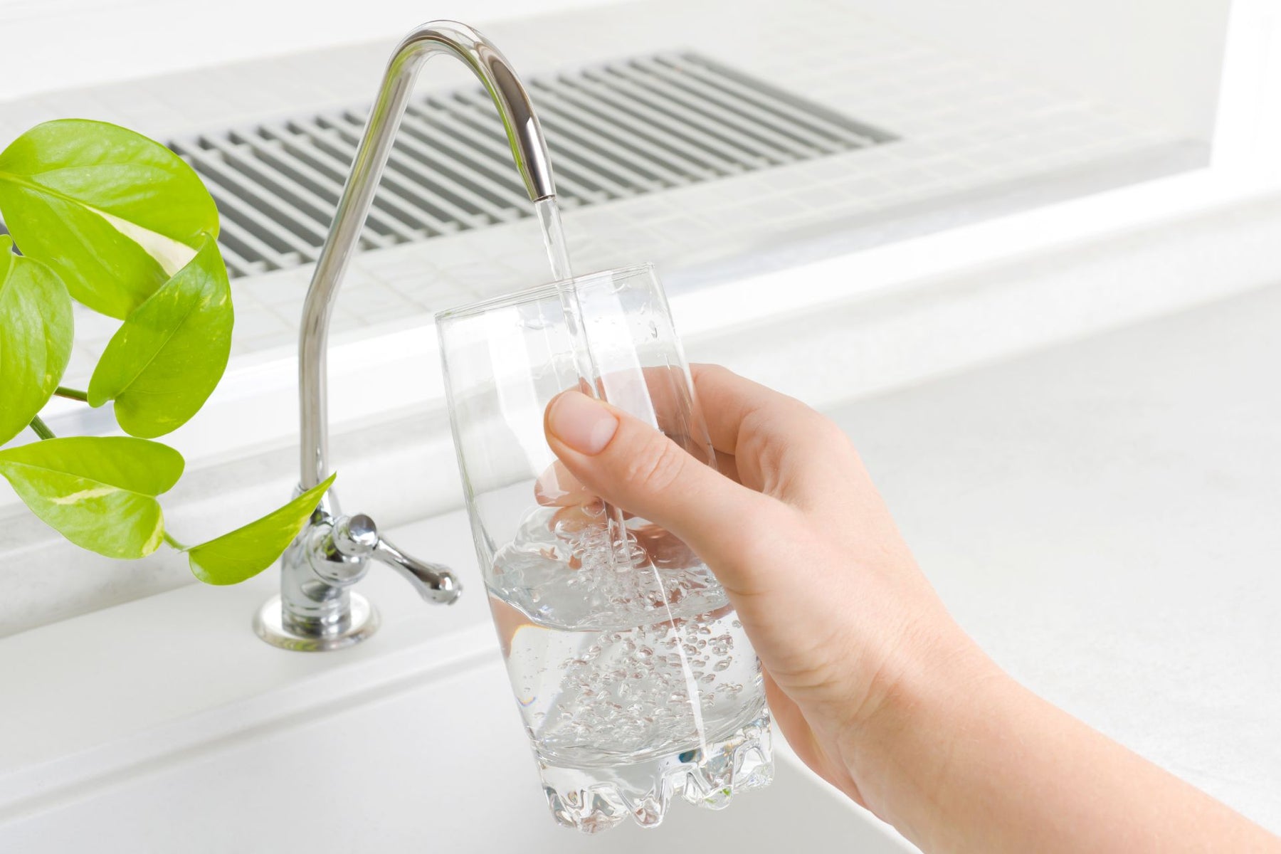 A person filling up a glass of water from the tap
