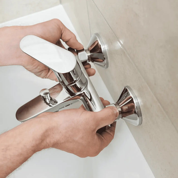 A person installs a brand new single handle faucet in a bathtub 