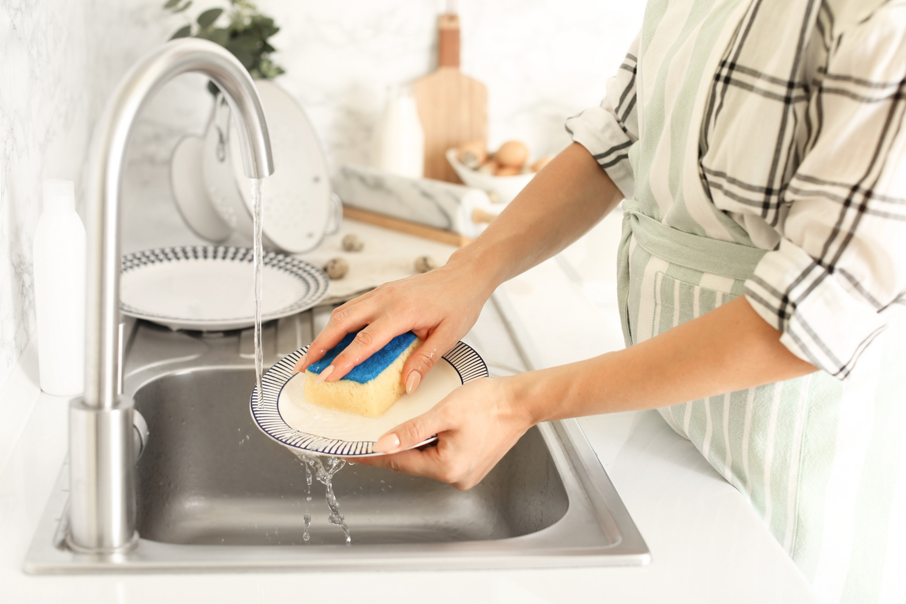 Person washing dirty dishes in a single sink