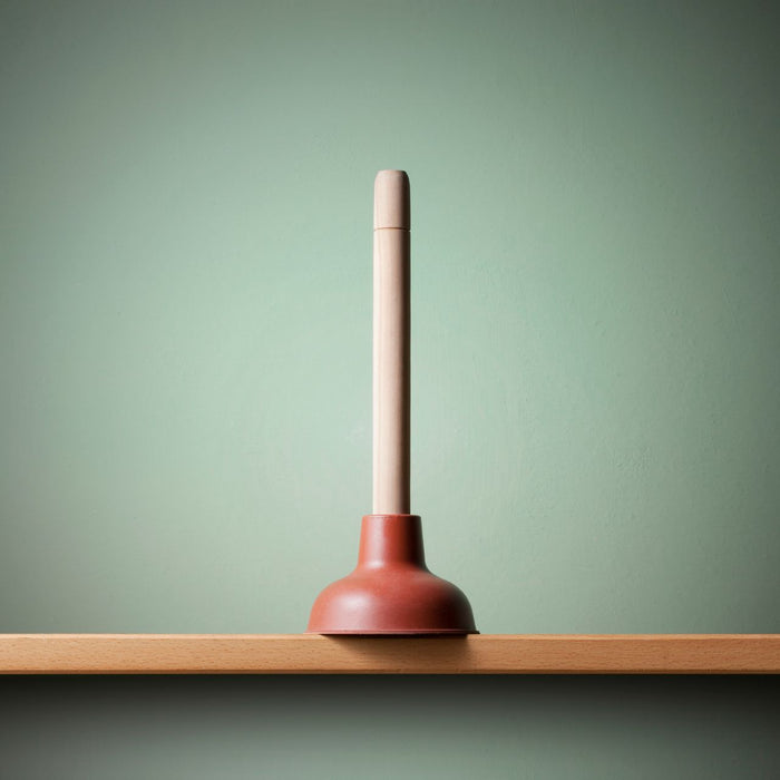 A standard plunger on top of a wooden plank