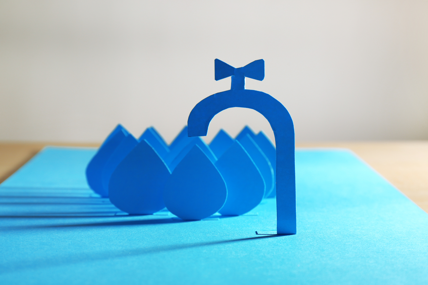 Blue paper cutouts of faucet and water droplets